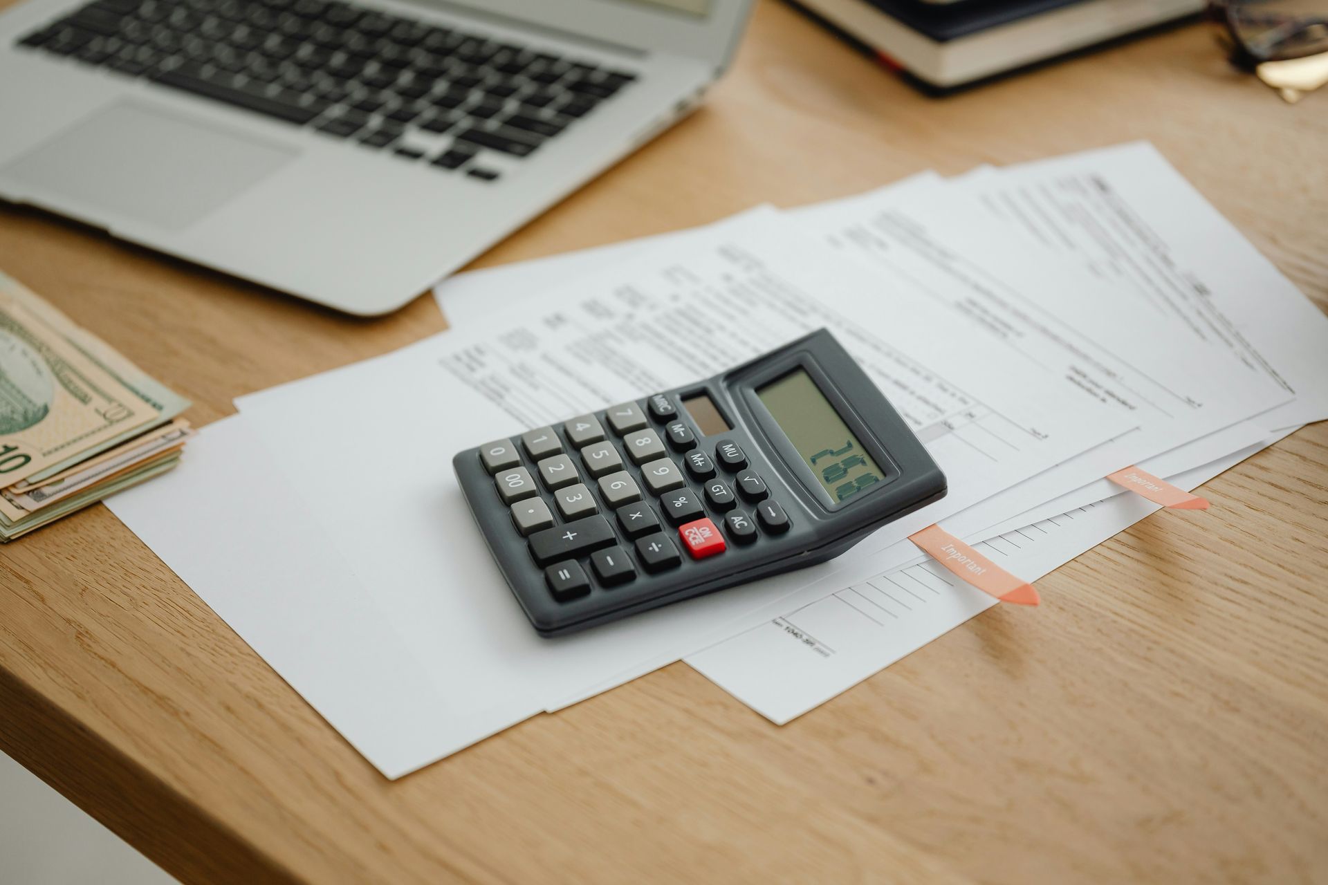 A calculator is sitting on top of a table next to a laptop.