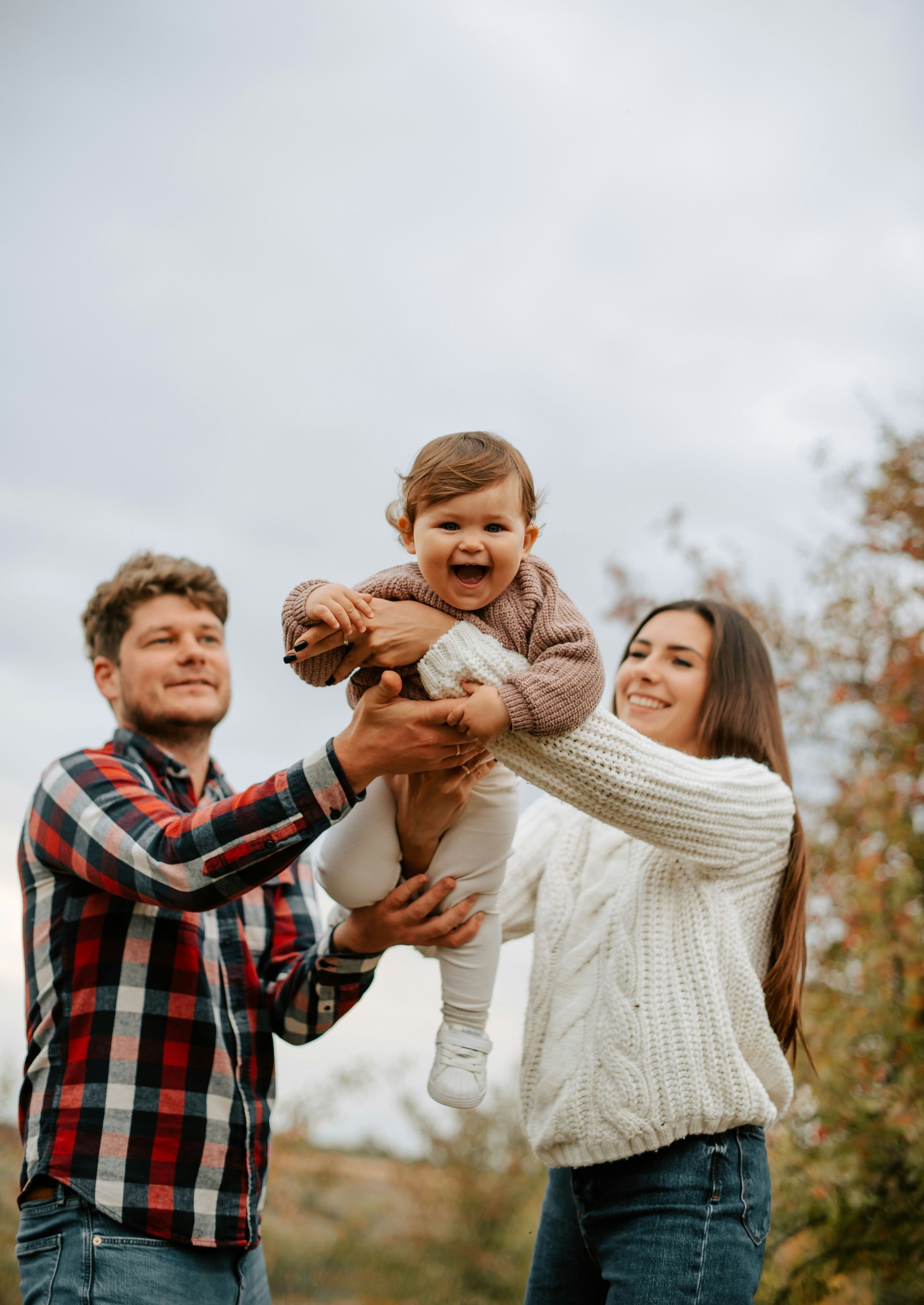 A man and a woman are holding a baby in their arms.