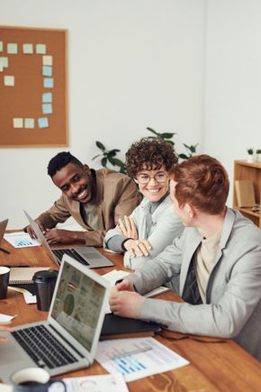 A group of people are sitting at a table with laptops.