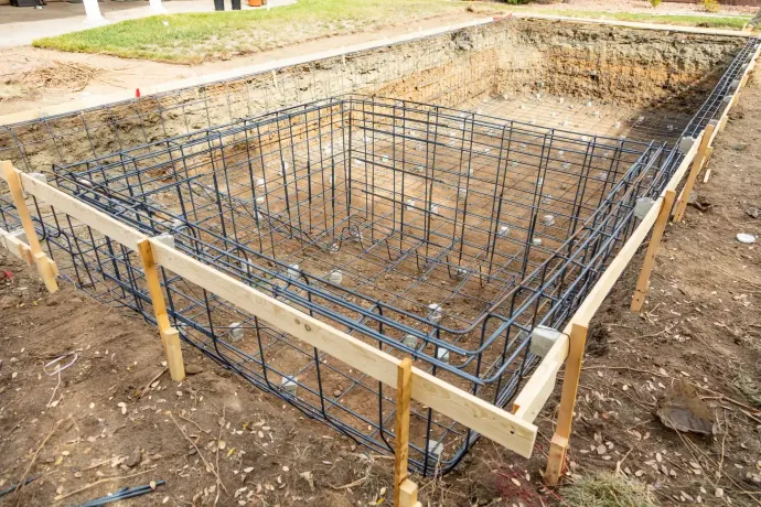 Piscina rettangolare in costruzione, con struttura in tondini di ferro e cassaforma in legno.