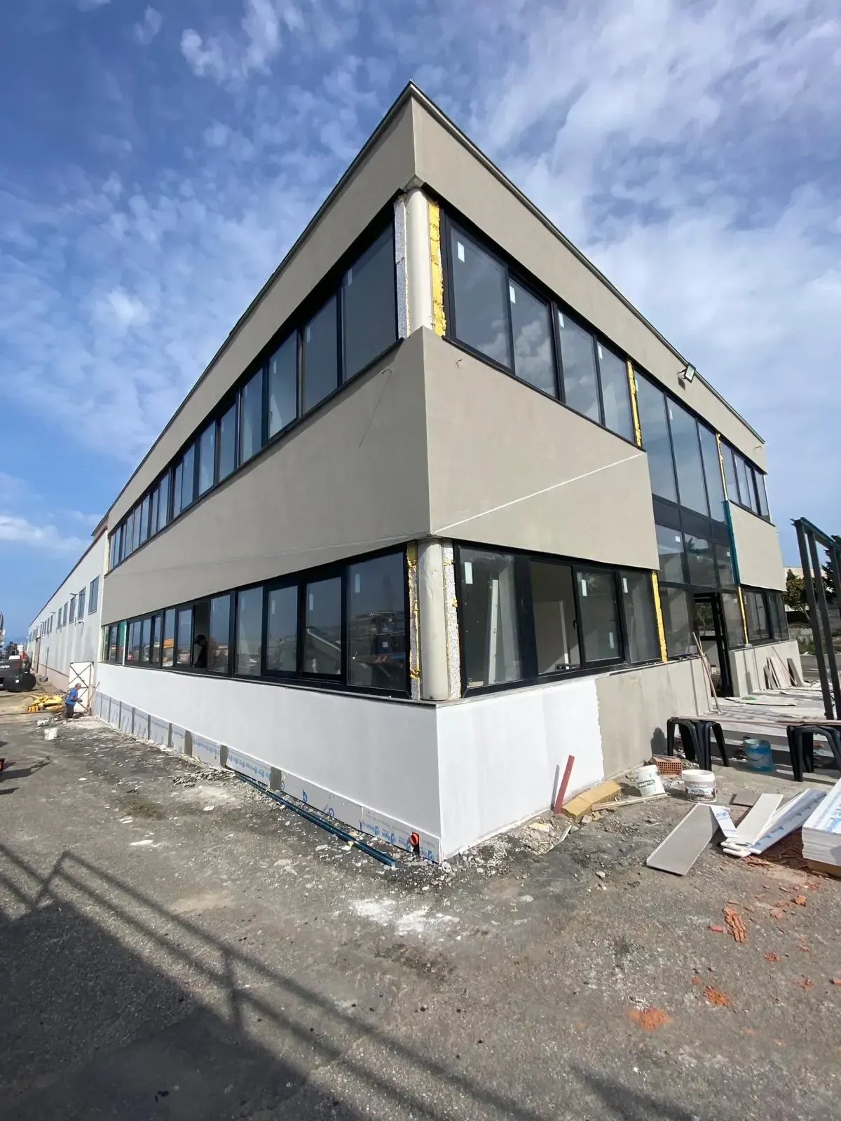 Una stanza in costruzione con impalcature, attrezzi e una finestra. Le pareti sono bianche.