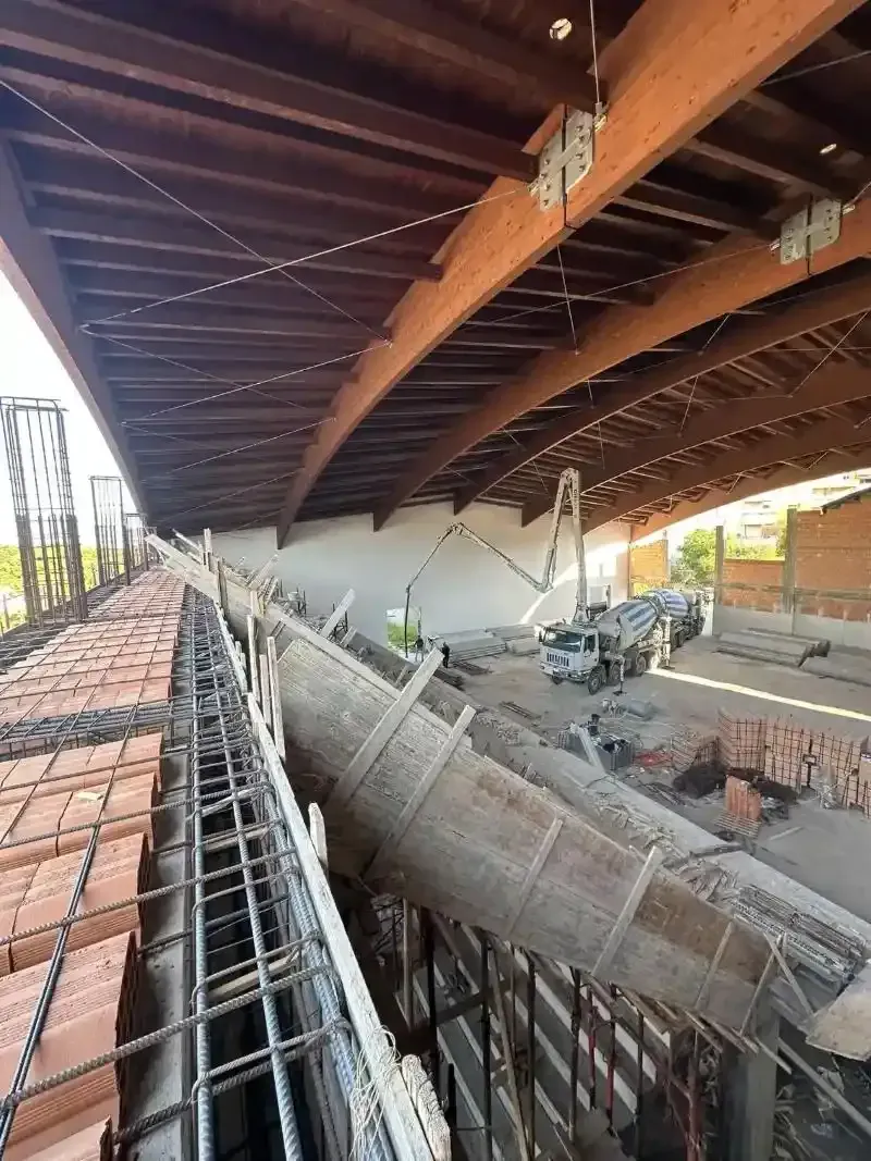 Cantiere: il calcestruzzo viene colato tramite un braccio in un'area chiusa sotto un tetto in legno.