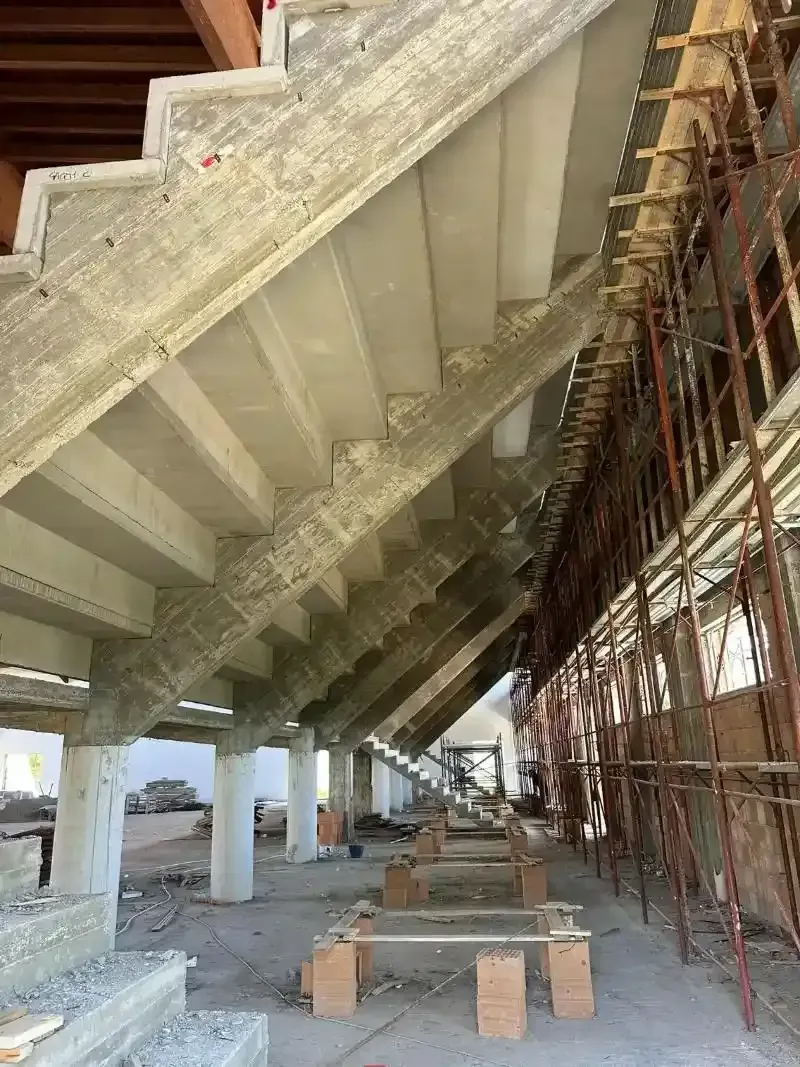 Scala in cemento in costruzione, sostenuta da impalcature e colonne.