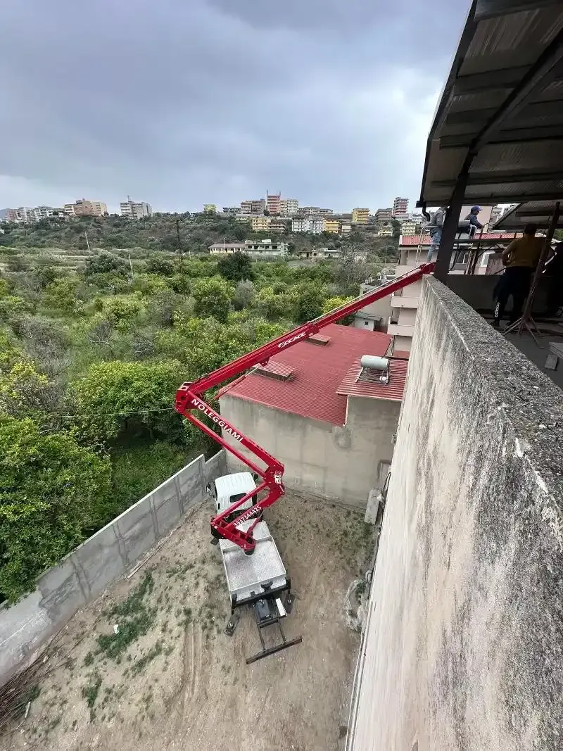 Un'autopompa per calcestruzzo estende il braccio sopra un edificio per versare il calcestruzzo.