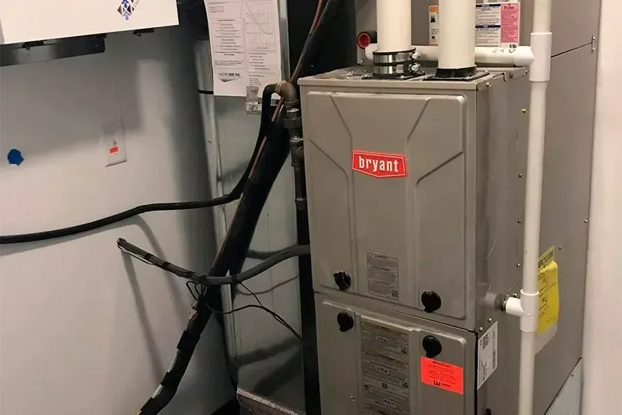 A furnace is sitting in a room next to a refrigerator.