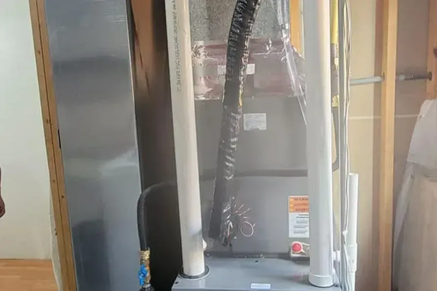 A hose is coming out of a furnace in a room.