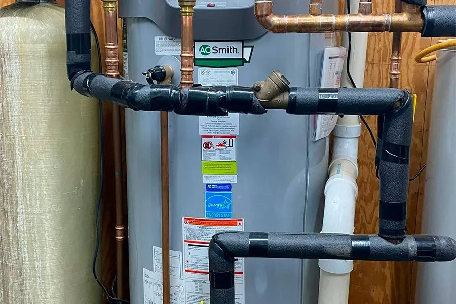 A water heater is surrounded by pipes in a room.