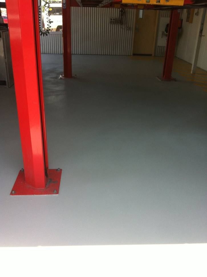 Red Car Lift Posts in a Garage With Light Gray Painted Floor — Australian Epoxy Floors in Gladstone, QLD