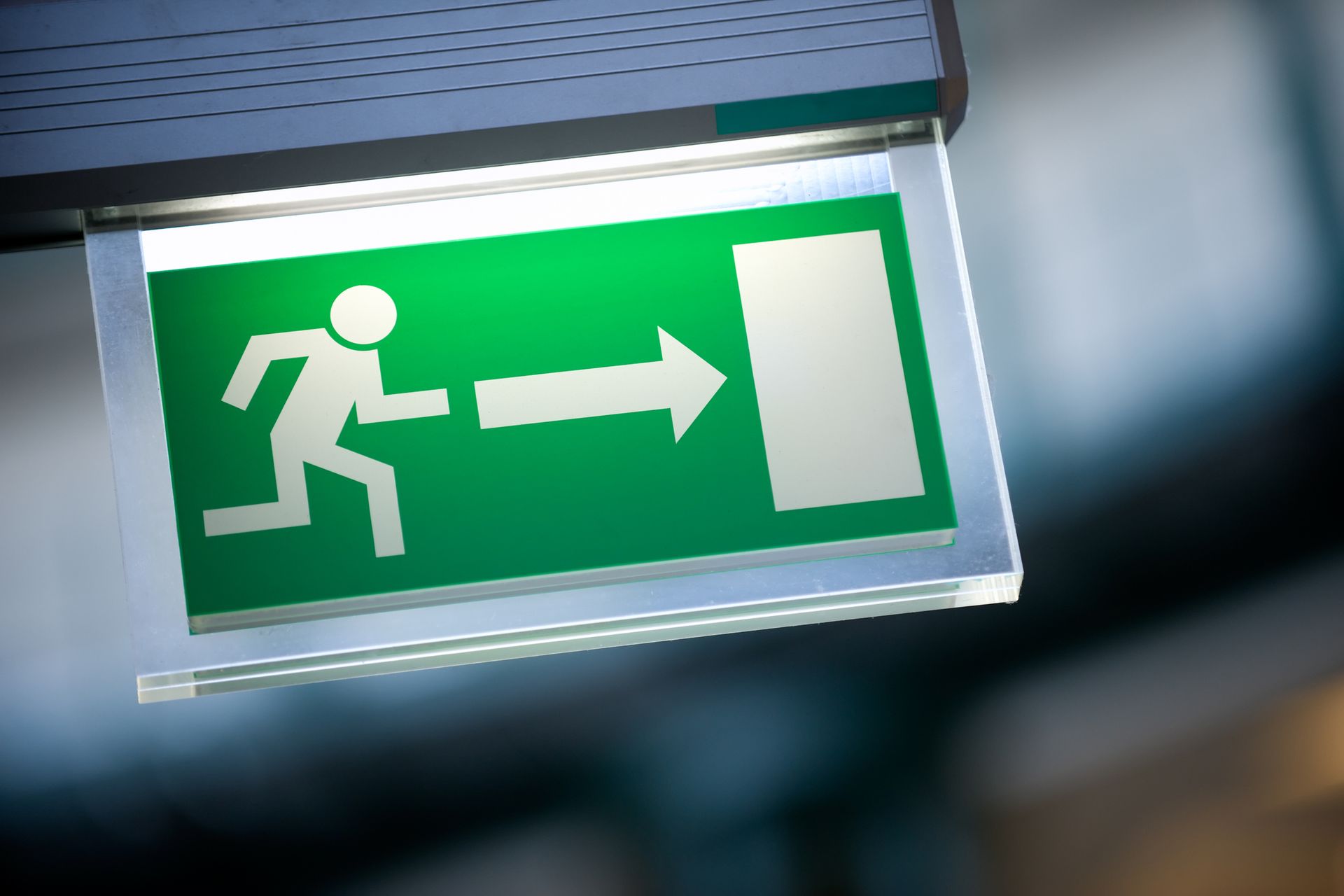 Green emergency exit sign; running person with arrow pointing right.
