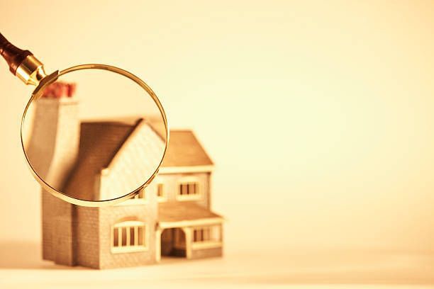 Magnifying glass over miniature house; inspection concept.