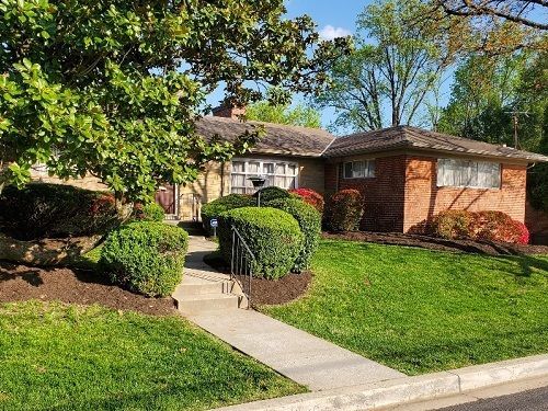 a brick house with a lush green lawn and trees in front of it .