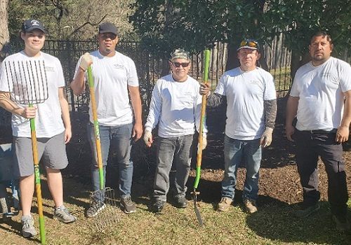 a group of men are standing next to each other holding gardening tools .