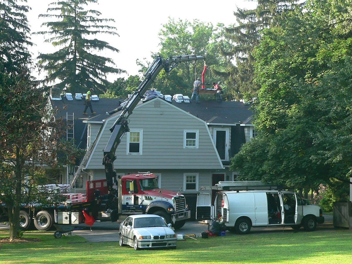 Workers using a crane in fixing the roof — Mount Wolf, PA — Dover Roofing Services