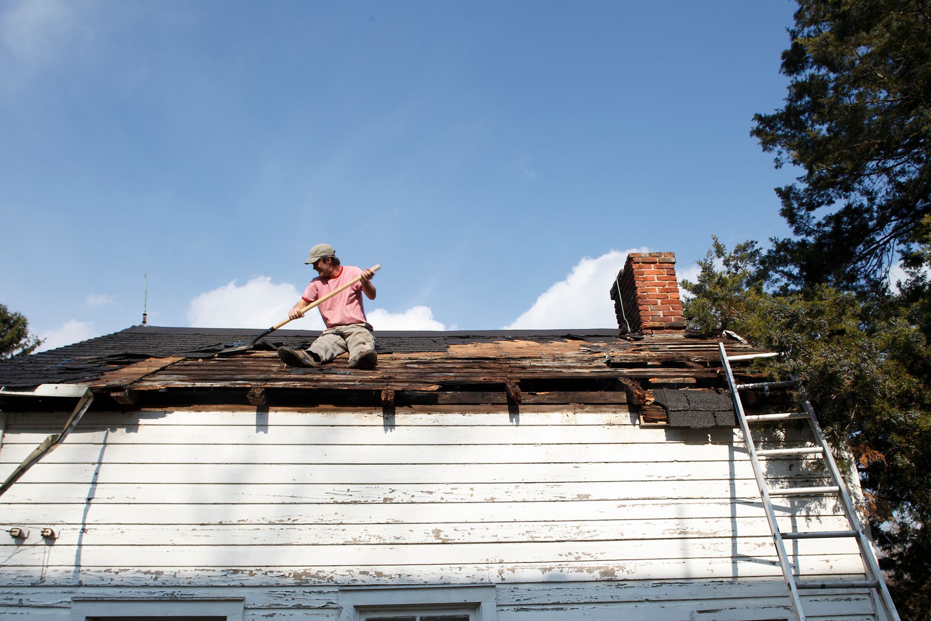 A man is sitting on the roof of a house. — Mount Wolf, PA — Dover Roofing Services