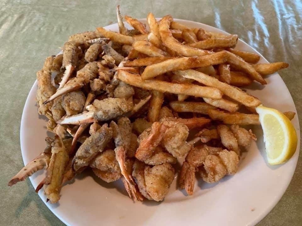 A white plate topped with fried shrimp and french fries on a table.