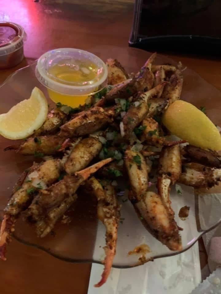 A plate of fried crab claws with a lemon wedge and dipping sauce.