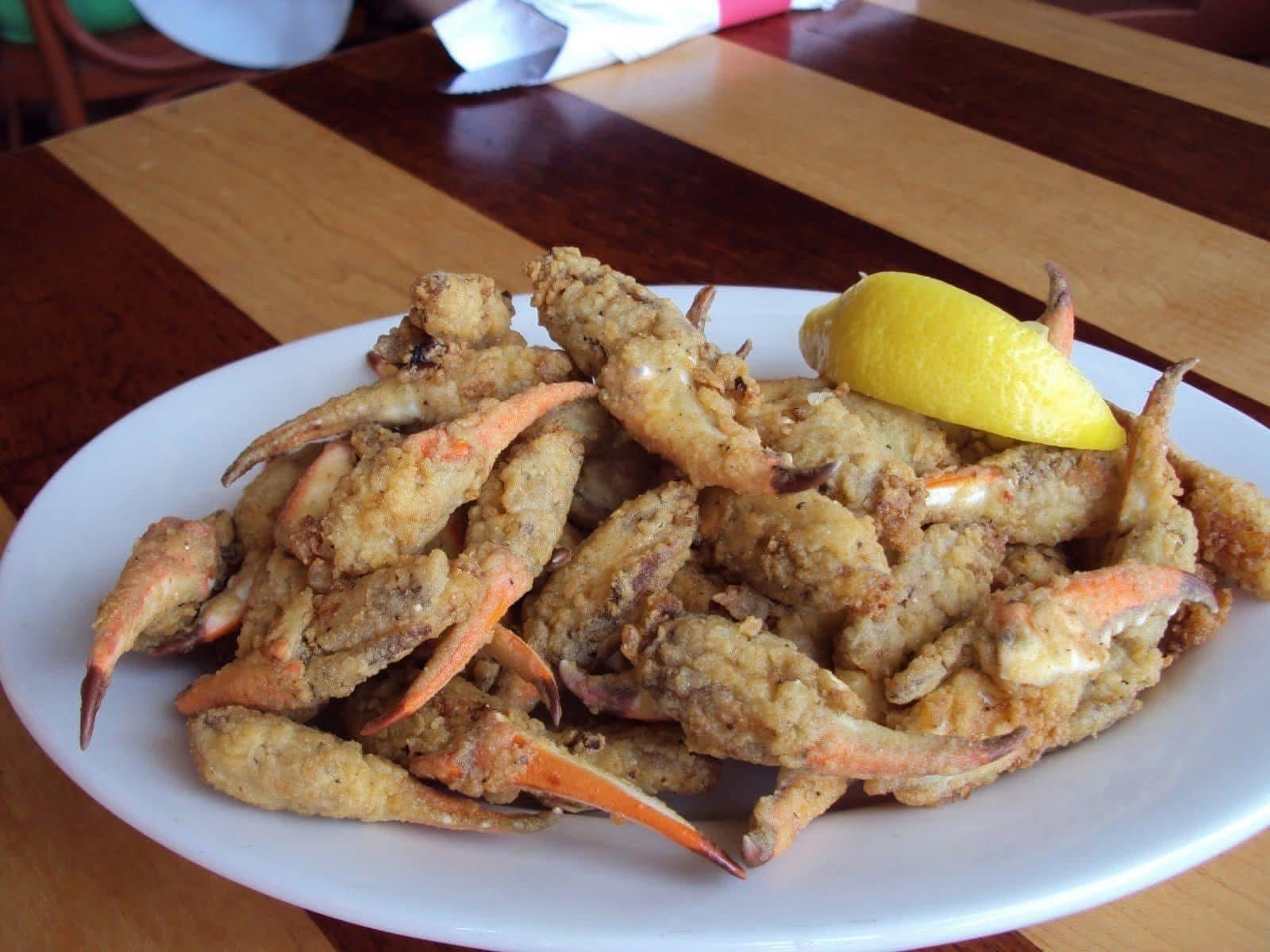 A plate of fried crabs with a slice of lemon on a wooden table
