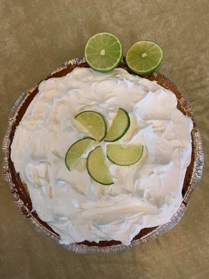 A key lime pie with whipped cream and lime slices on top