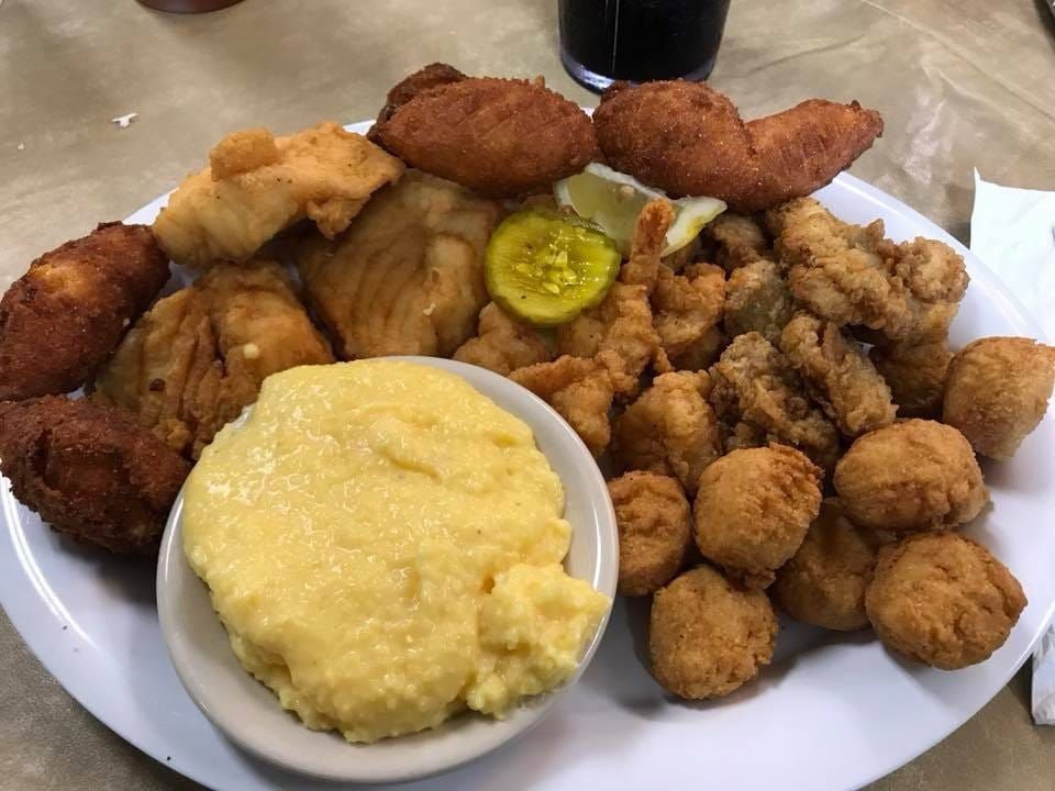 A white plate topped with fried food and a bowl of grits