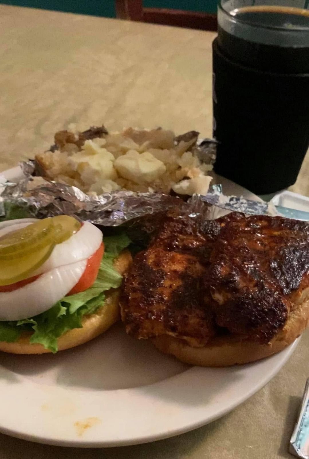 A plate of food with a sandwich and a glass of beer on a table.