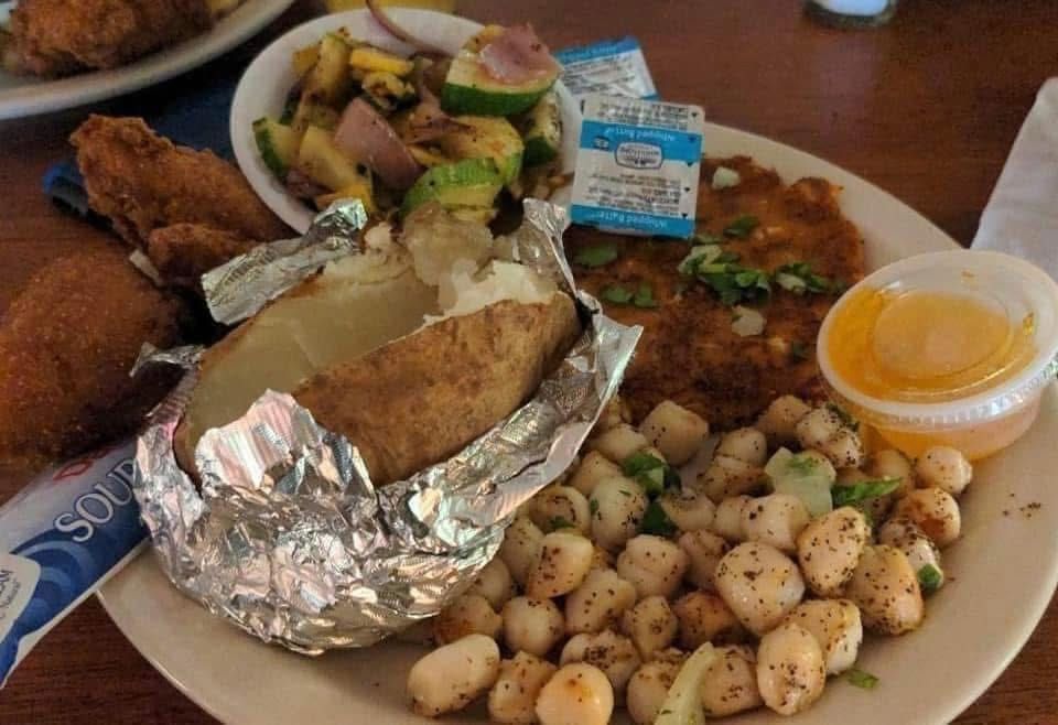 A plate of food with a baked potato and scallops