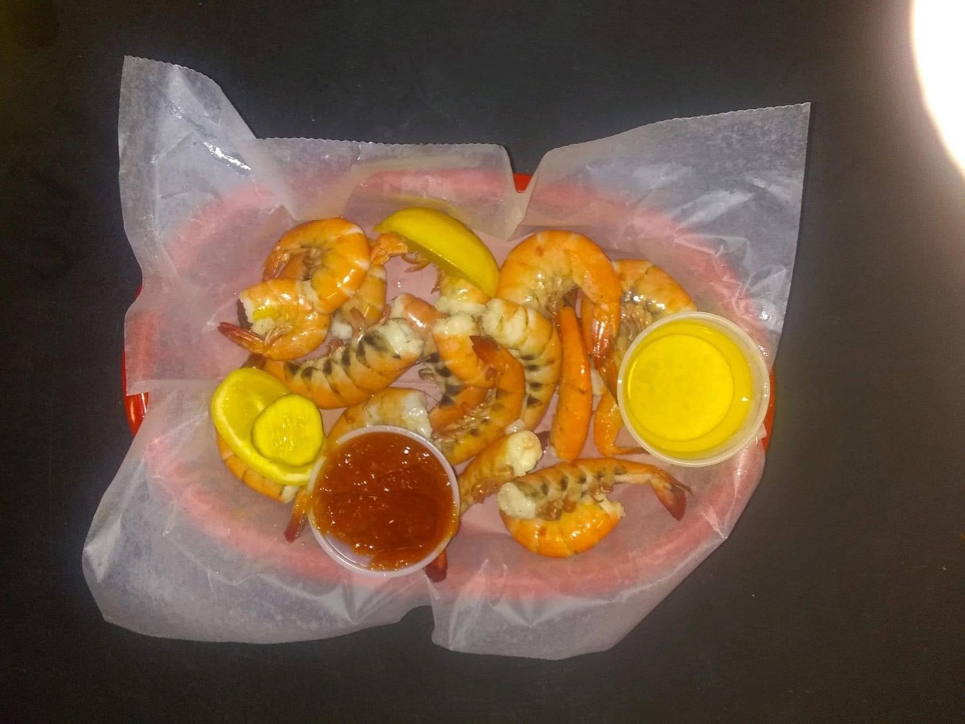 A basket of shrimp with sauces and pickles on a table