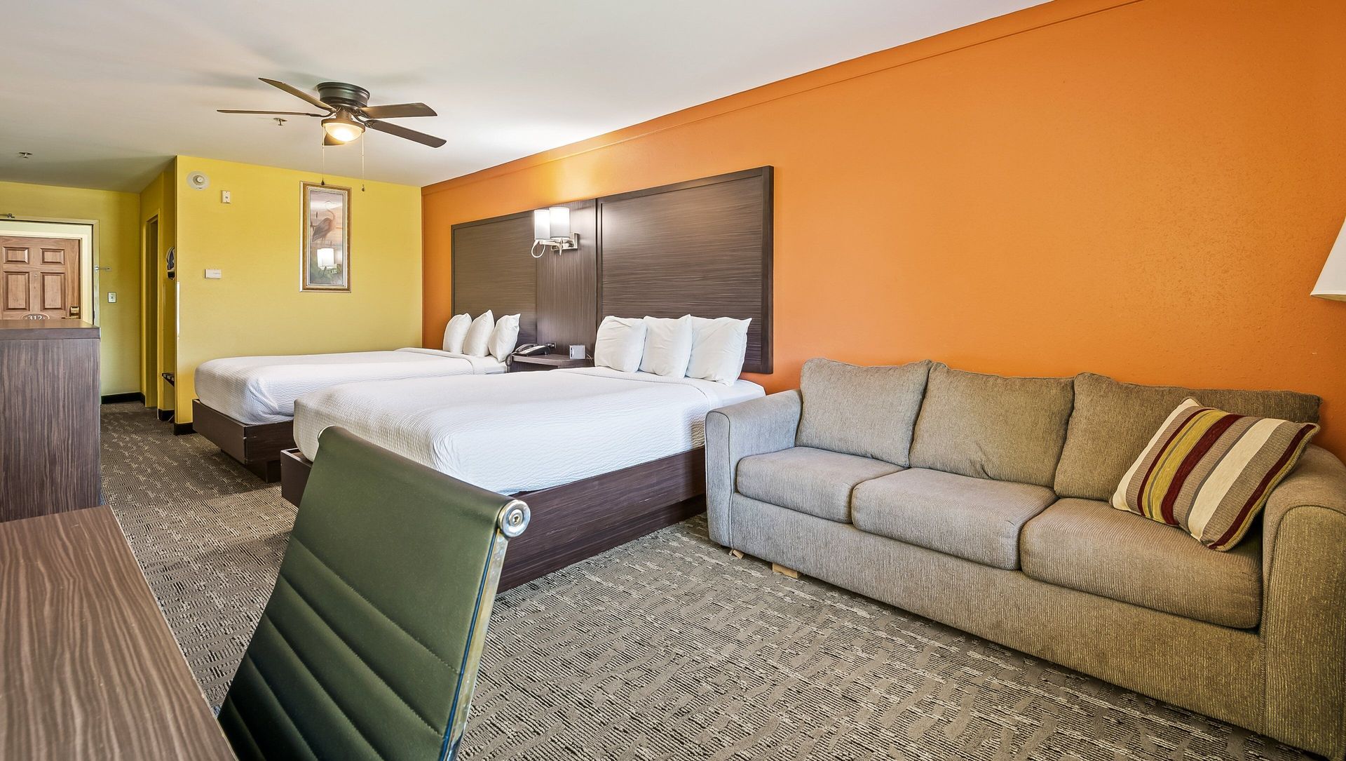 A hotel room with two beds , a couch , and a desk.