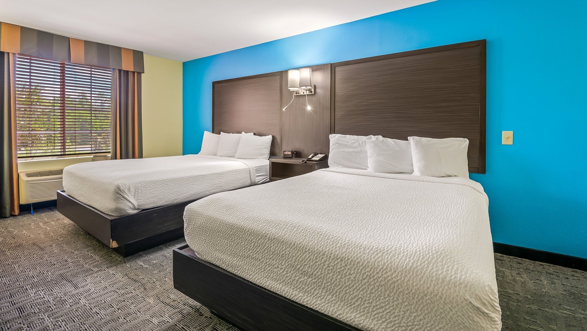 A hotel room with two beds and a blue wall