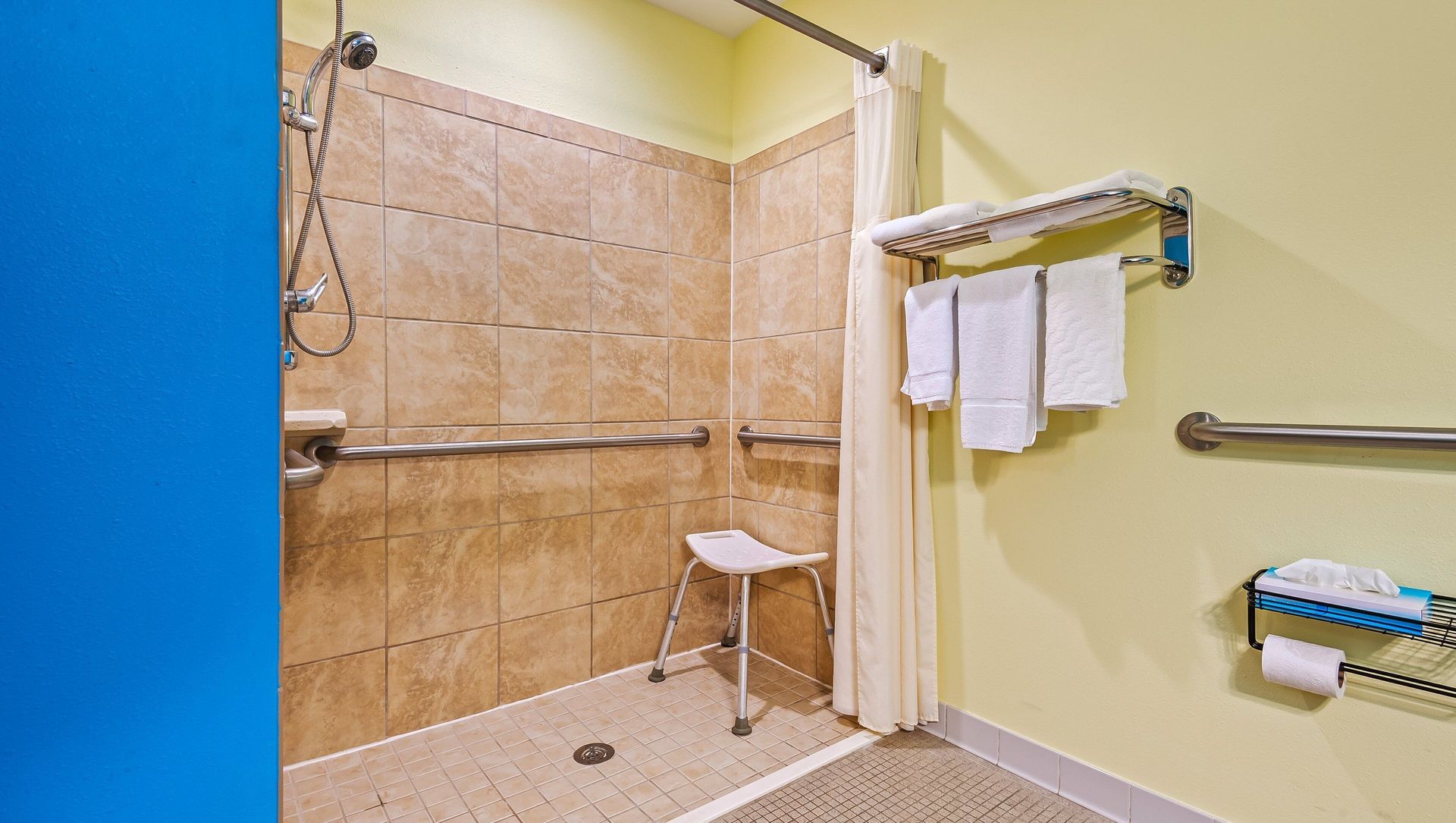 A bathroom with a walk in shower and a stool.