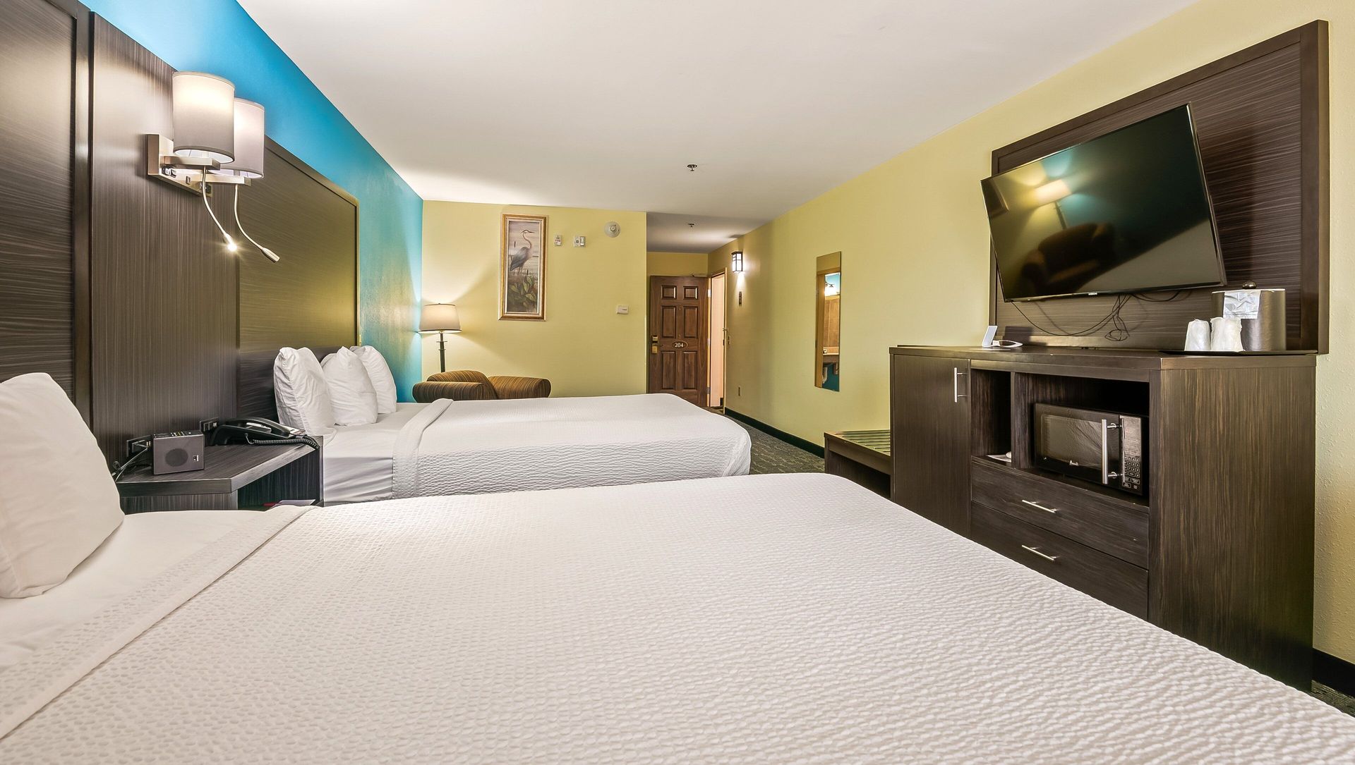 A hotel room with two beds and a flat screen tv
