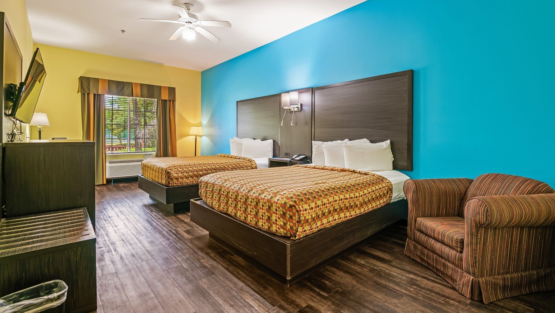 A hotel room with two beds , a chair and a television.