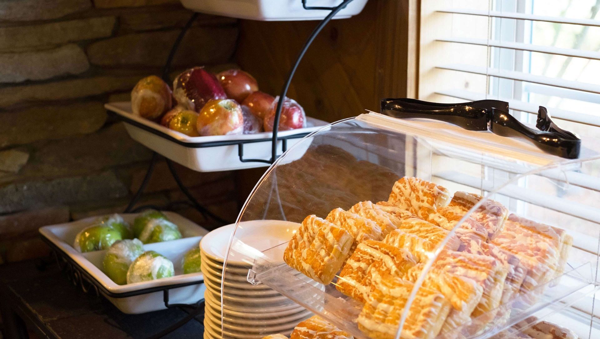 A display of pastries and fruit on a table next to a window.
