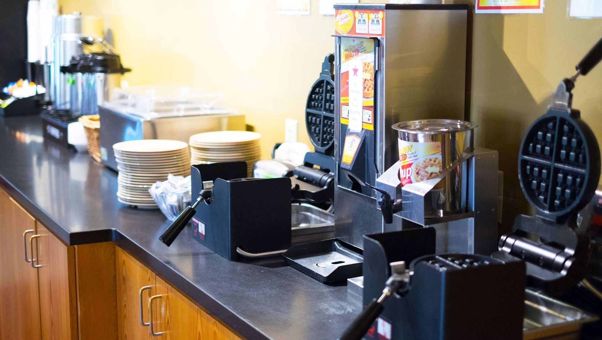 A kitchen with a lot of appliances and plates on the counter.