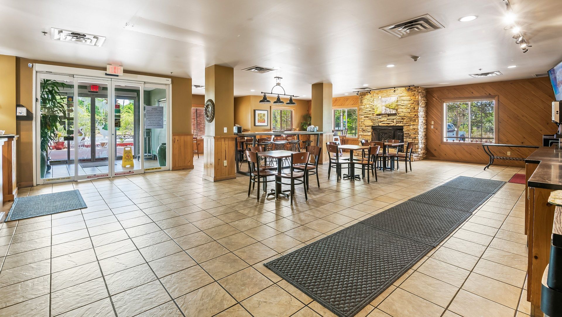 A hotel lobby with tables and chairs and a fireplace.