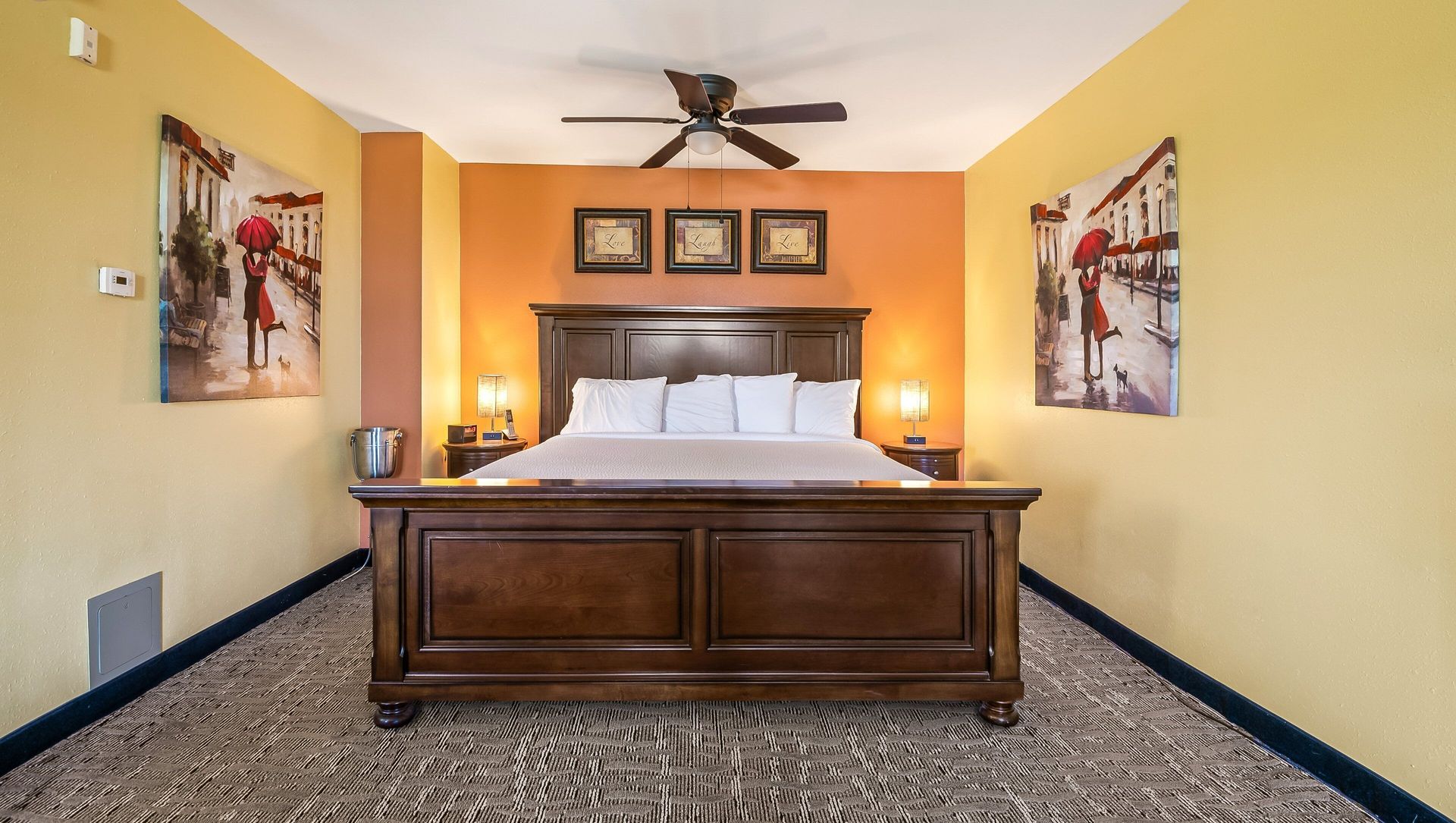 A hotel room with a king size bed and a ceiling fan.