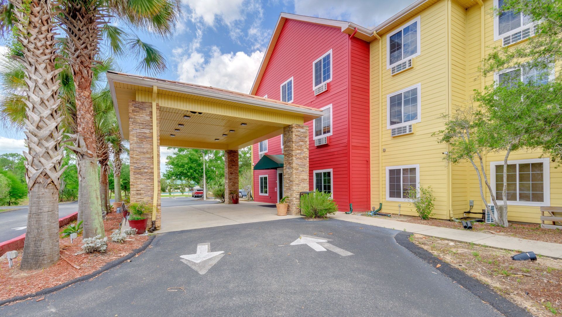 A red and yellow building with a palm tree in front of it.