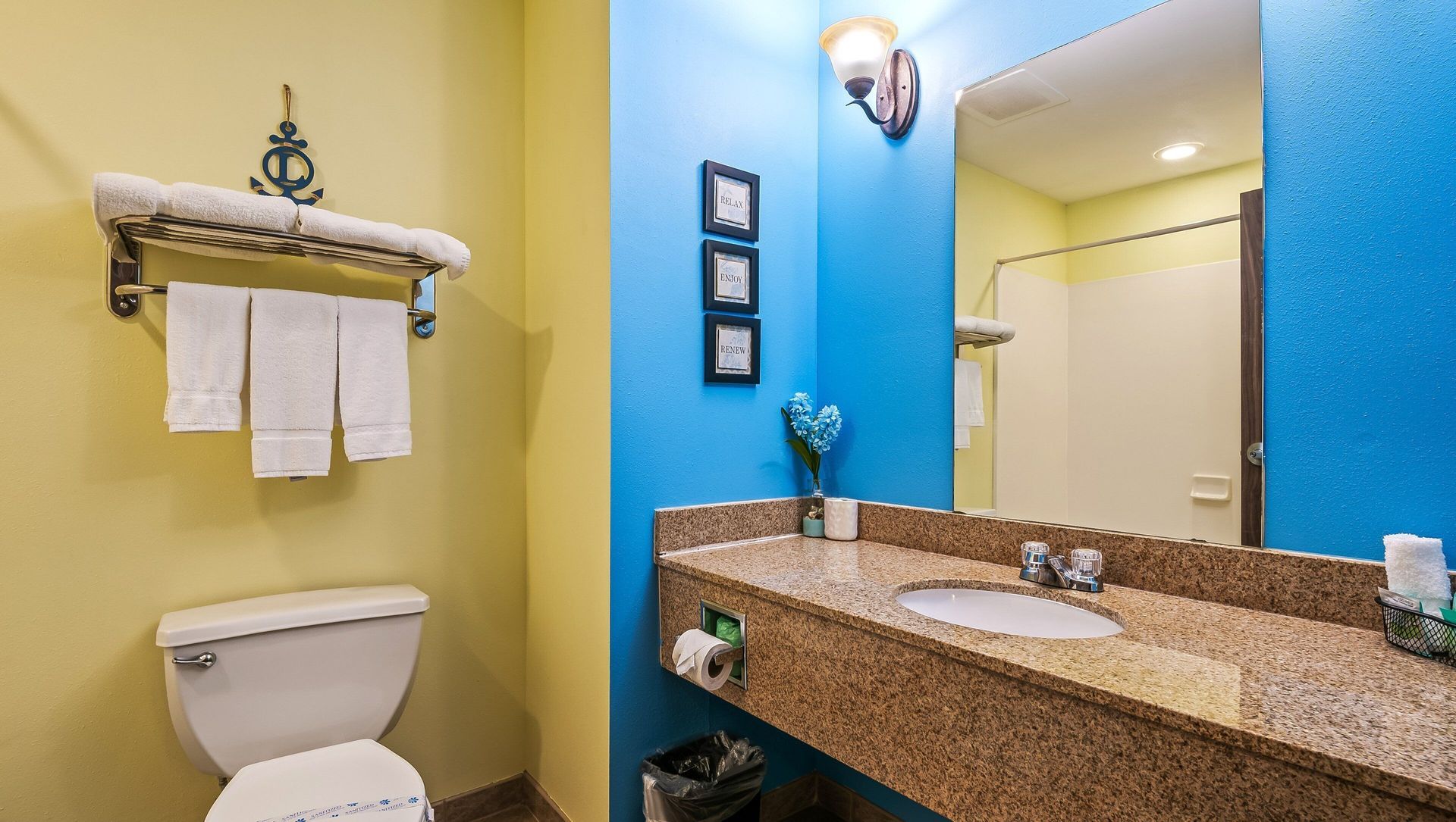 A bathroom with a toilet , sink and mirror.
