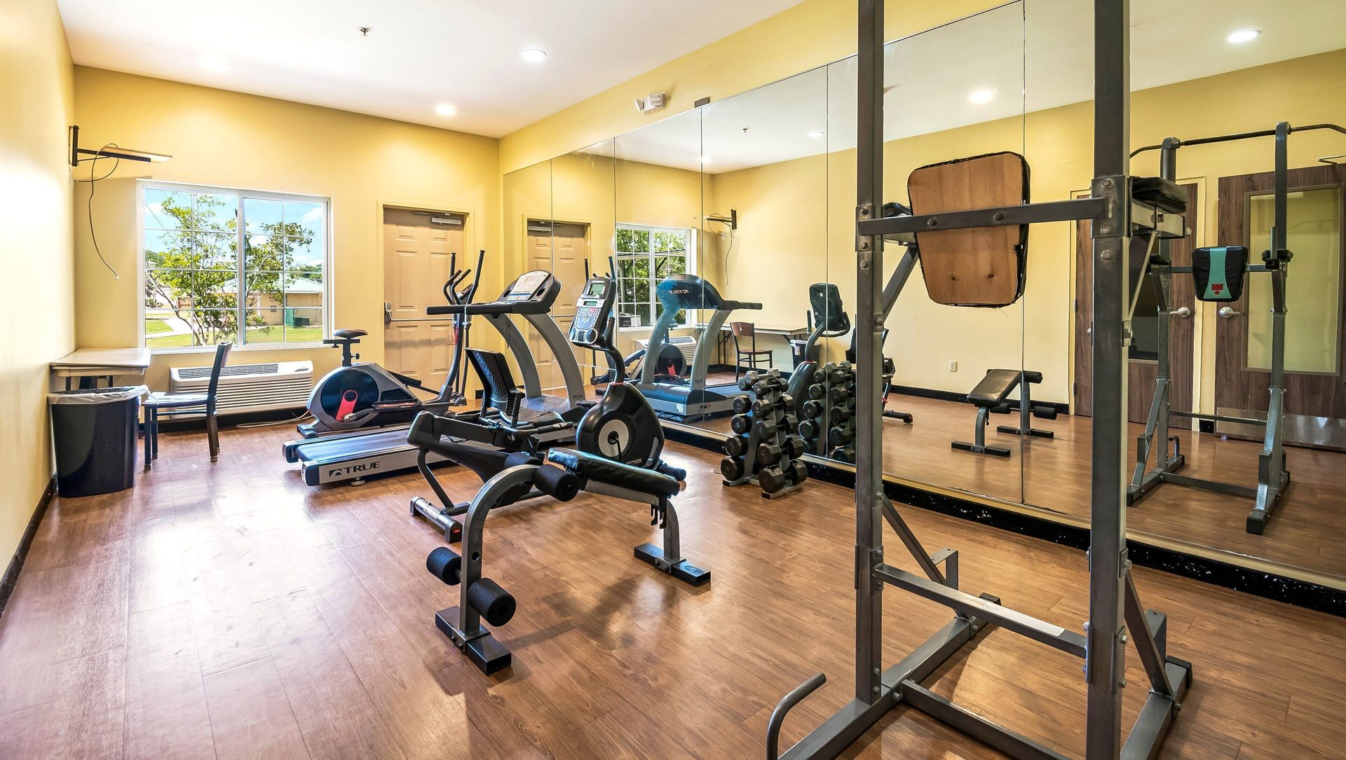 A gym with a lot of exercise equipment and a large mirror.