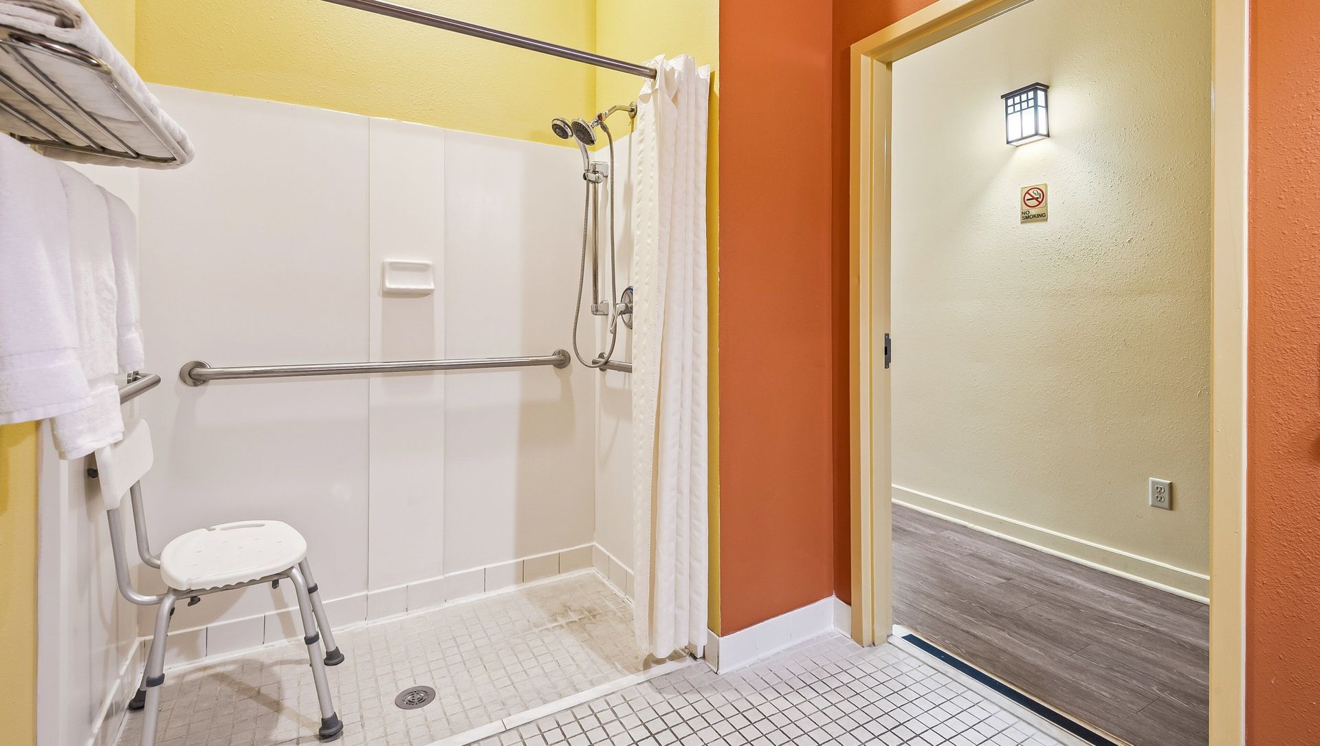 A bathroom with a walk in shower and a stool.