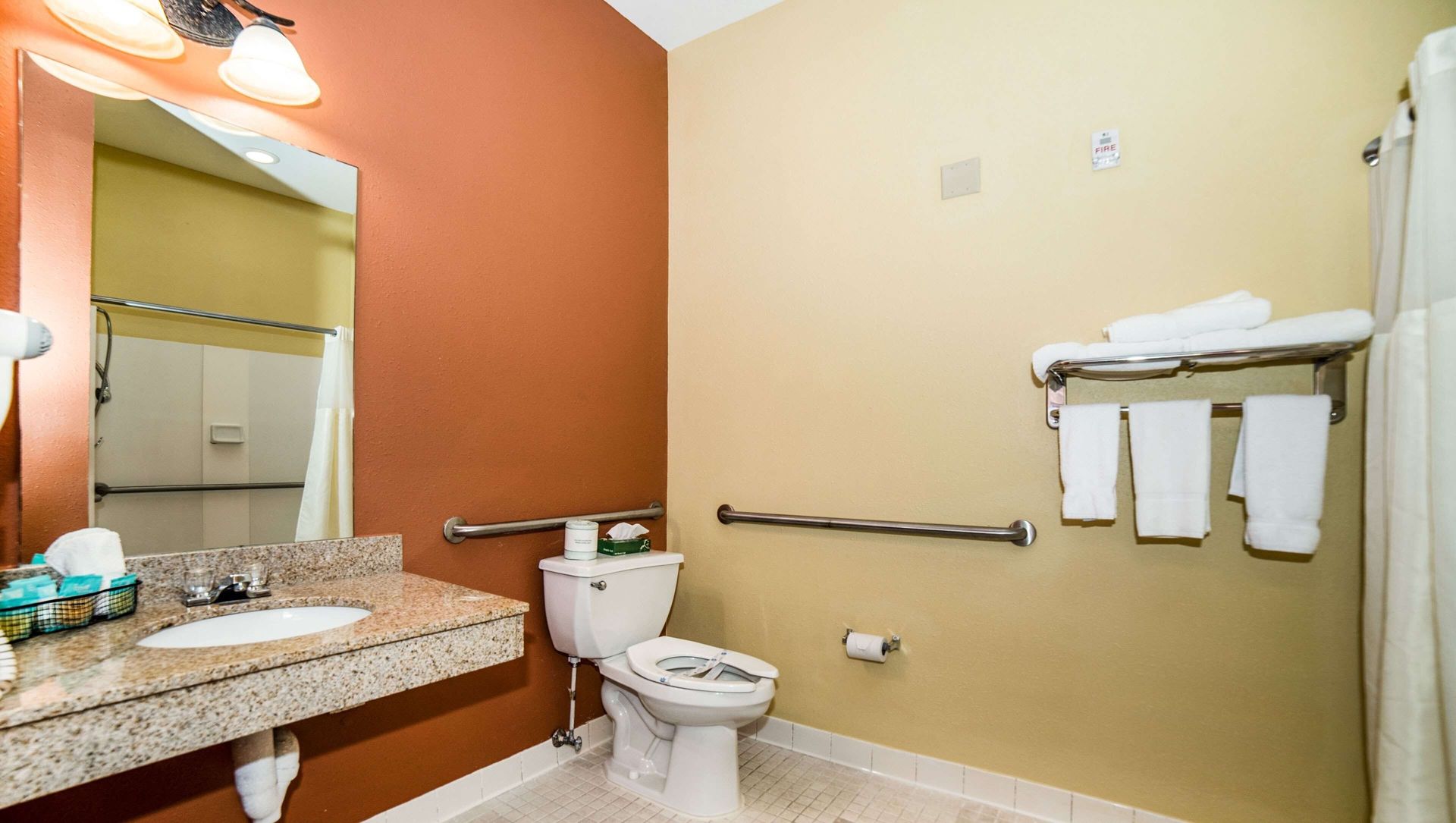 A bathroom with a toilet , sink and mirror.
