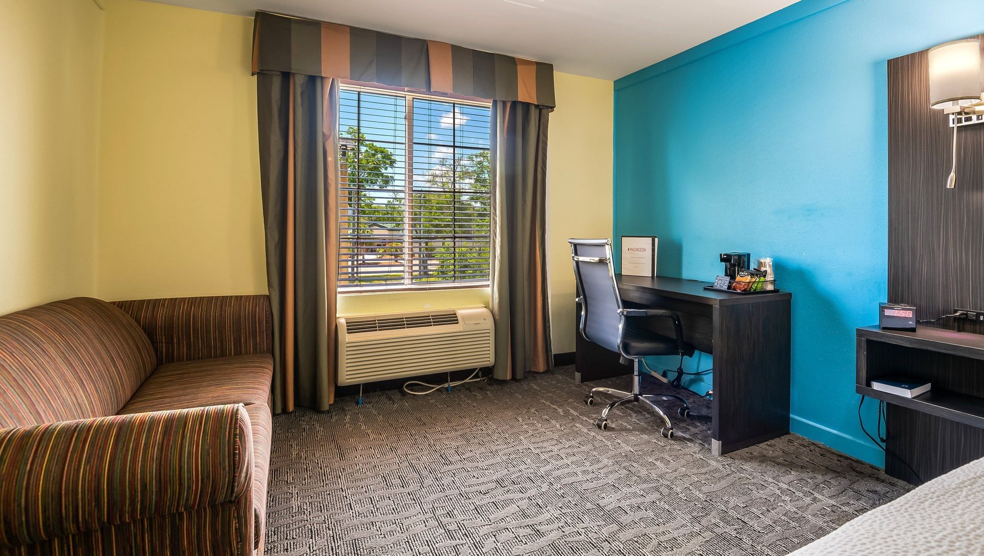 A hotel room with a couch , desk and chair.