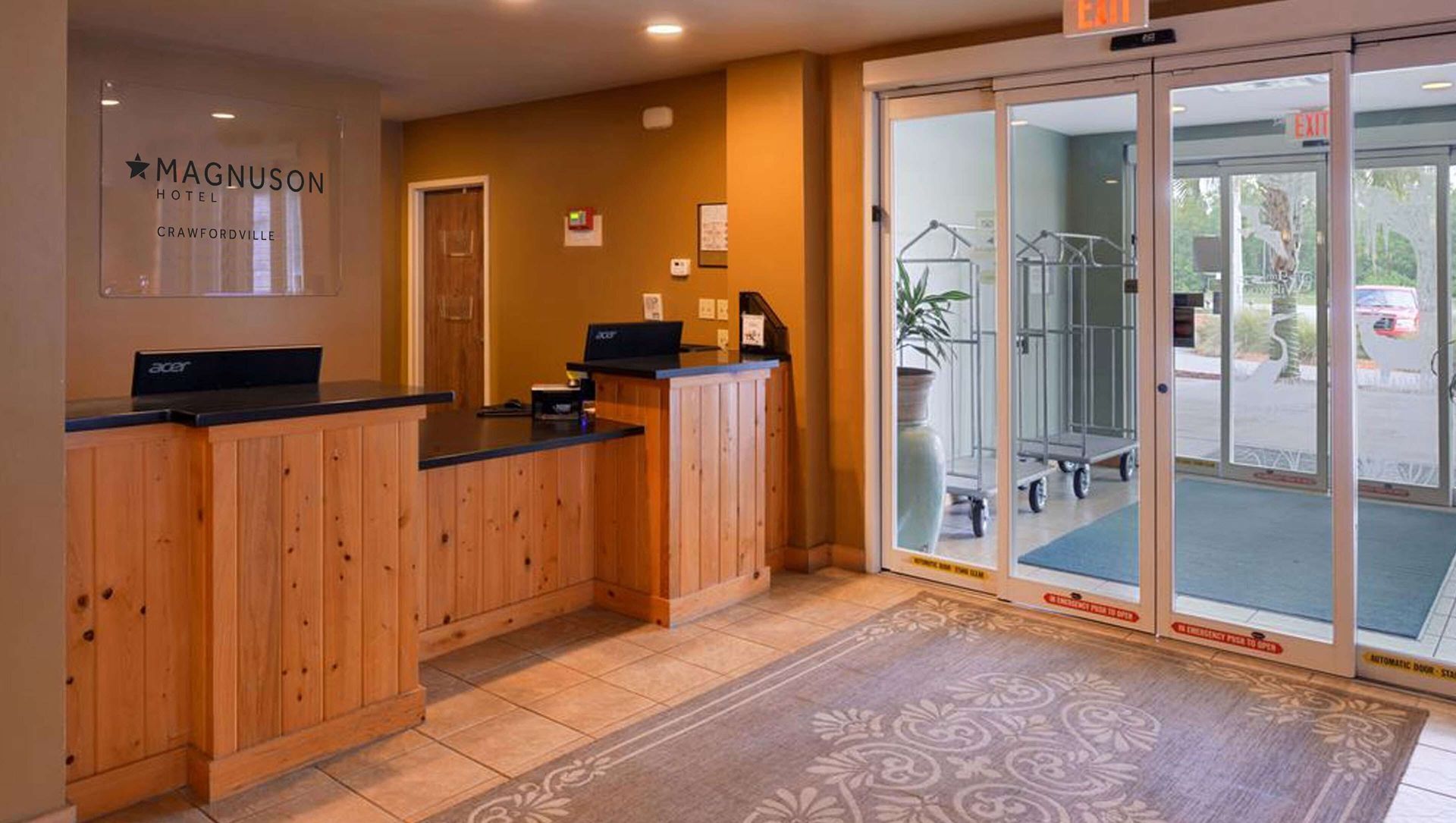 A hotel lobby with a wooden counter and sliding glass doors.