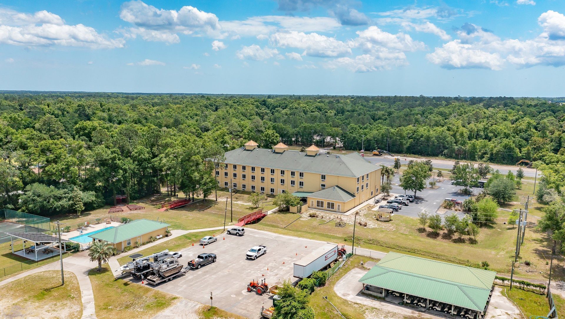 An aerial view of a hotel surrounded by trees and a parking lot.