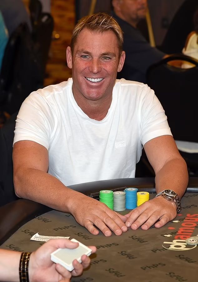 A man in a white shirt is sitting at a poker table