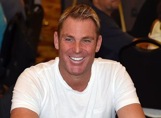 A man in a white shirt is smiling while sitting at a table.