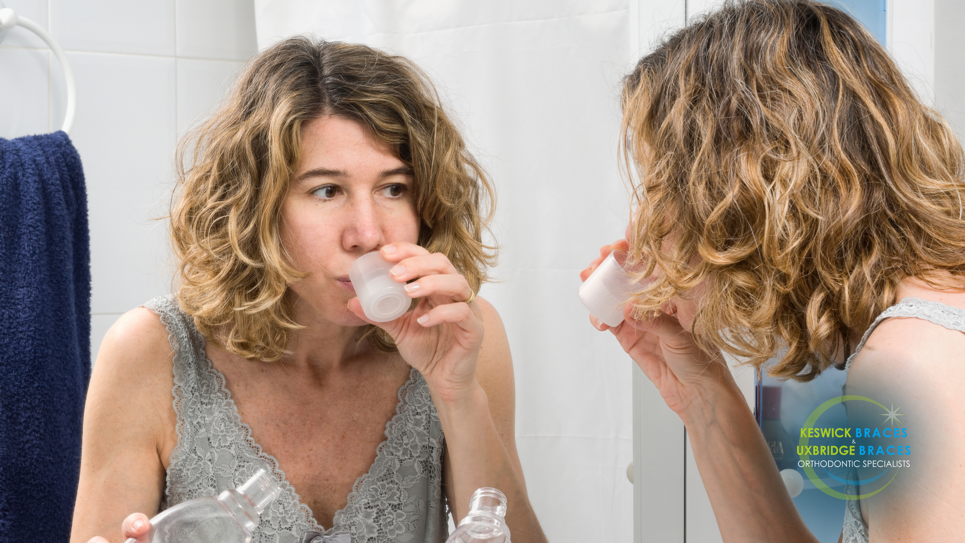 A woman is brushing her teeth in front of a mirror.