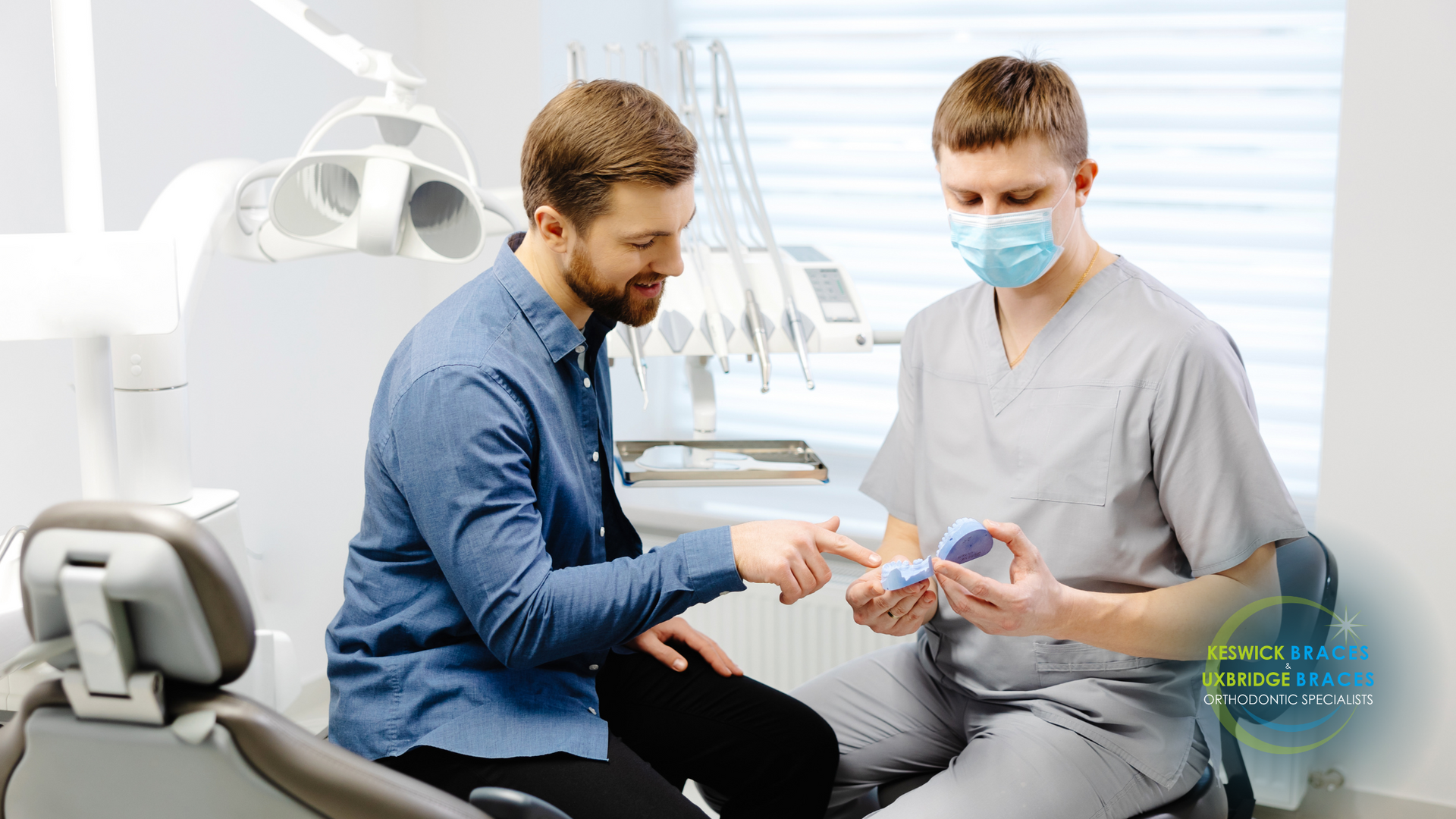 A man is sitting in a dental chair talking to a dentist.