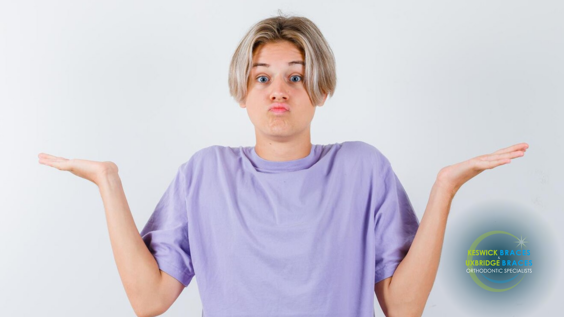 A young man in a purple shirt is shrugging his shoulders.