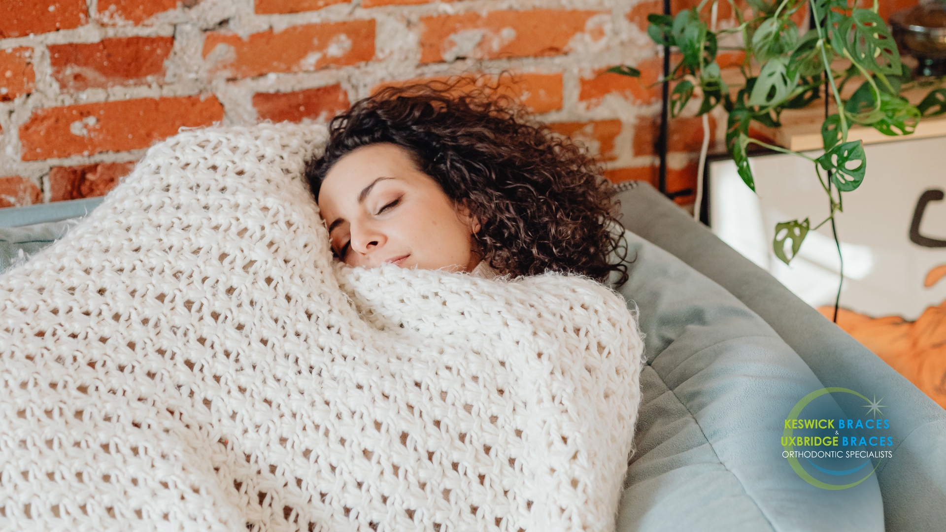 A woman is sleeping on a bean bag chair wrapped in a blanket.