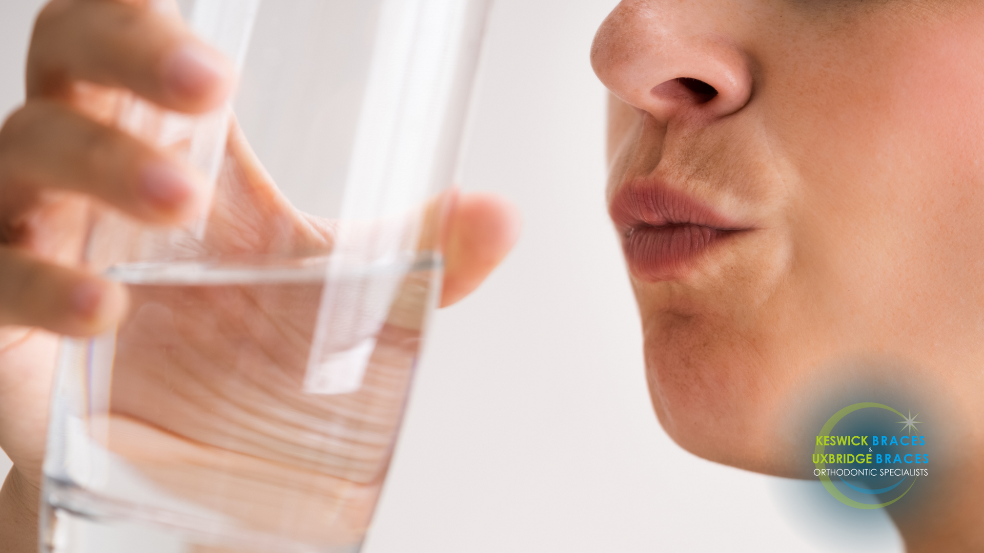 A woman is drinking a glass of water.